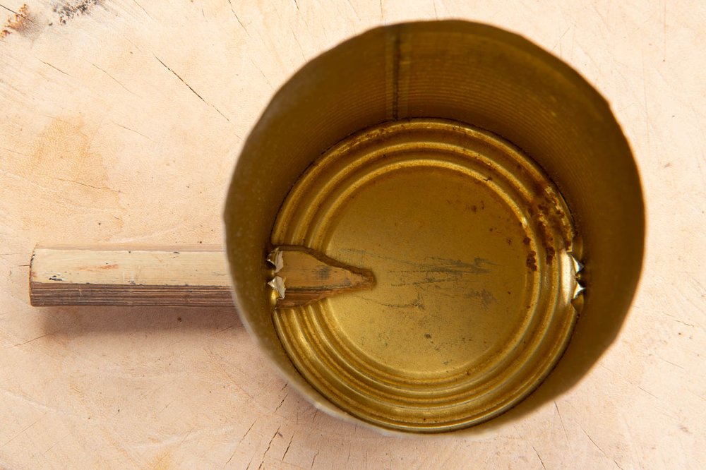 Tin can viewed from the open end showing bamboo tool through one of the
“T” shaped cut.