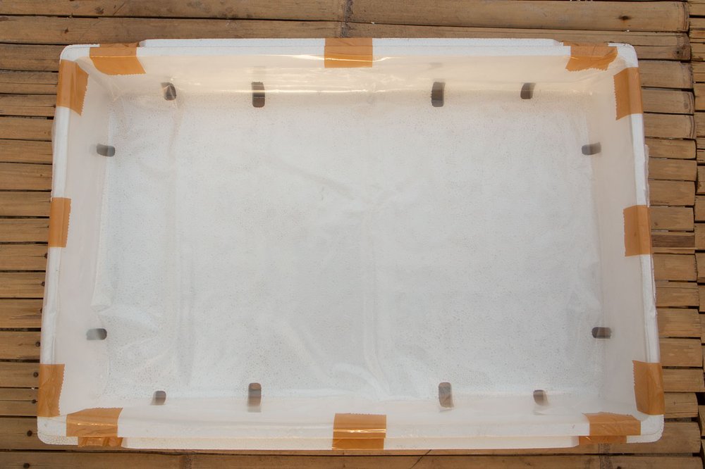 Lower half of a styrofoam box lined with PE plastic sheet.