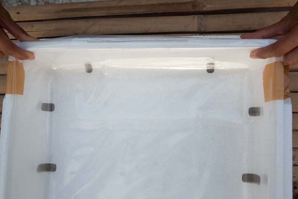 Folded ends of plastic liner positioned on the side of the grow box.