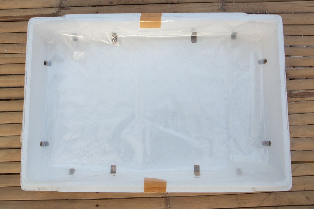 Plastic liner taped at the center of the length of the grow box.