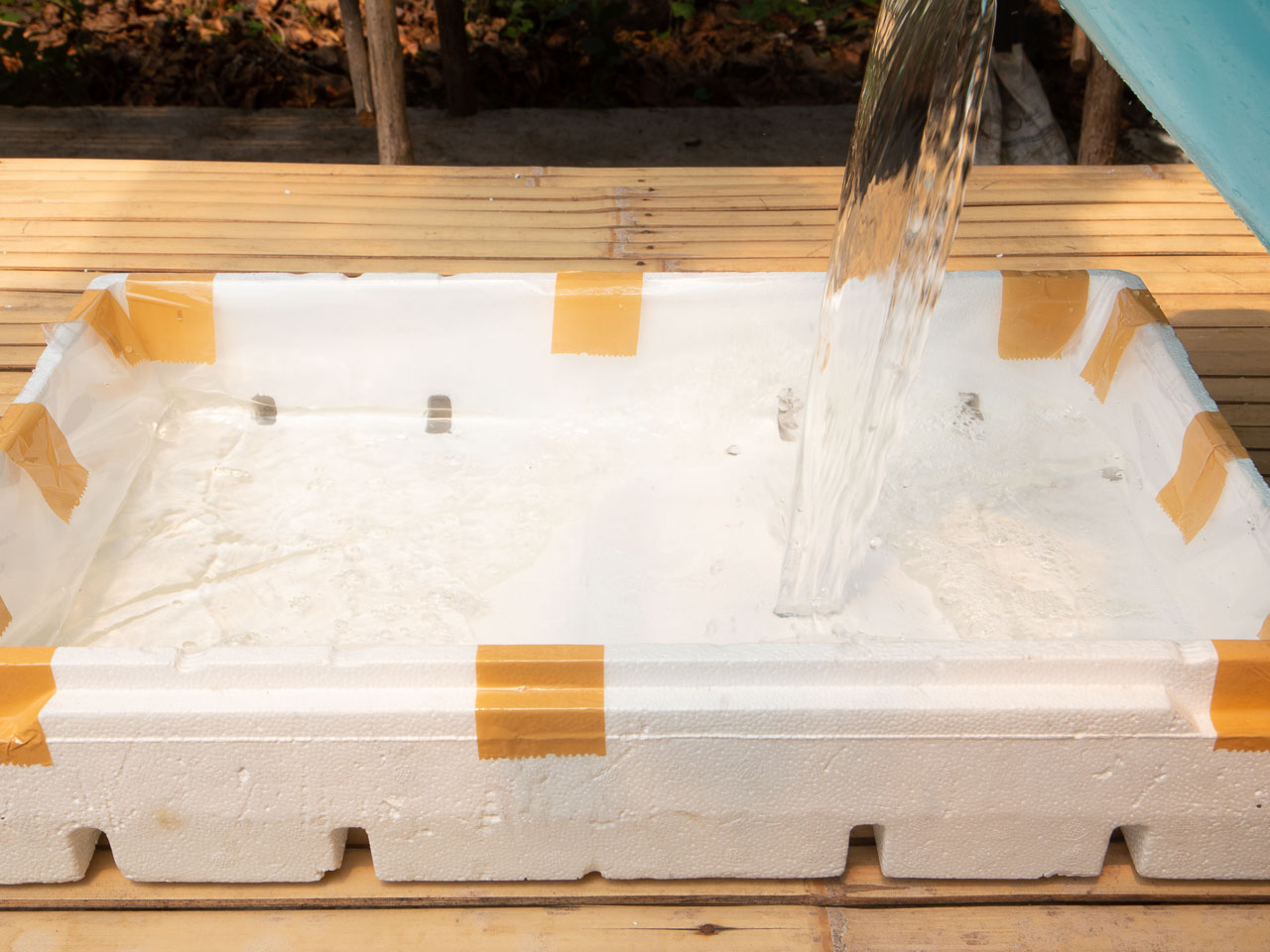 Water being poured on the bottom half of a grow box.