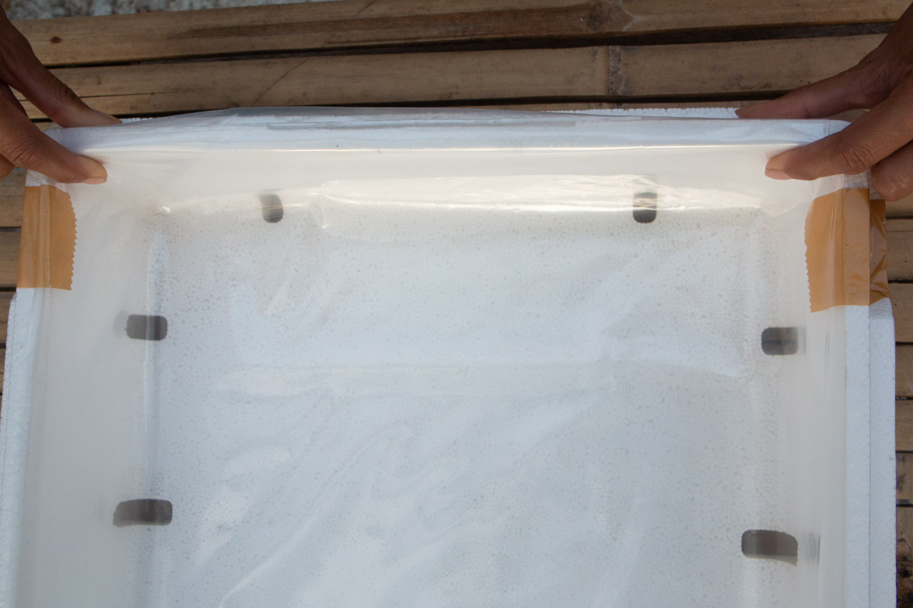 Folded ends of plastic liner positioned on the side of the grow box.